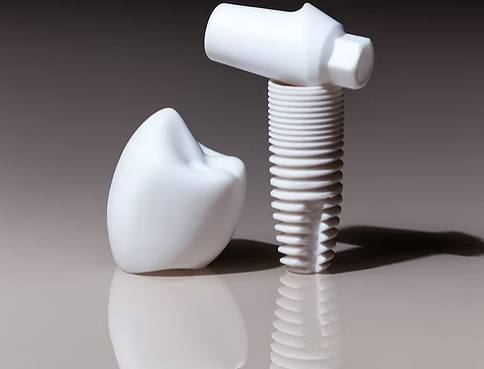 A close up shot of Zirconium Implants. A cap meant to take the place of a tooth sits next to the implant itself, a non-metallic white ceramic screw.